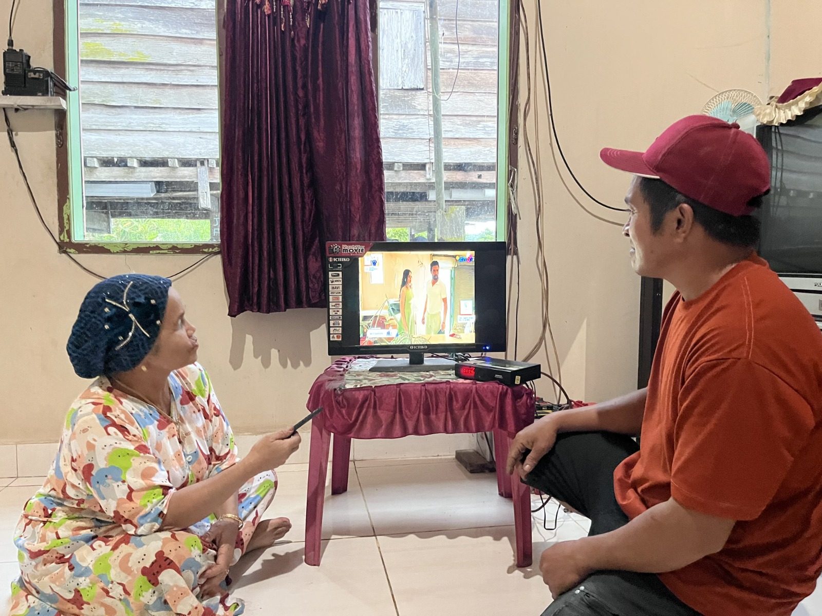 Ibu Mude dan masyarakat Desa Olu menikmati listrik PLN untuk aktivitas sehari-hari, termasuk menonton televisi