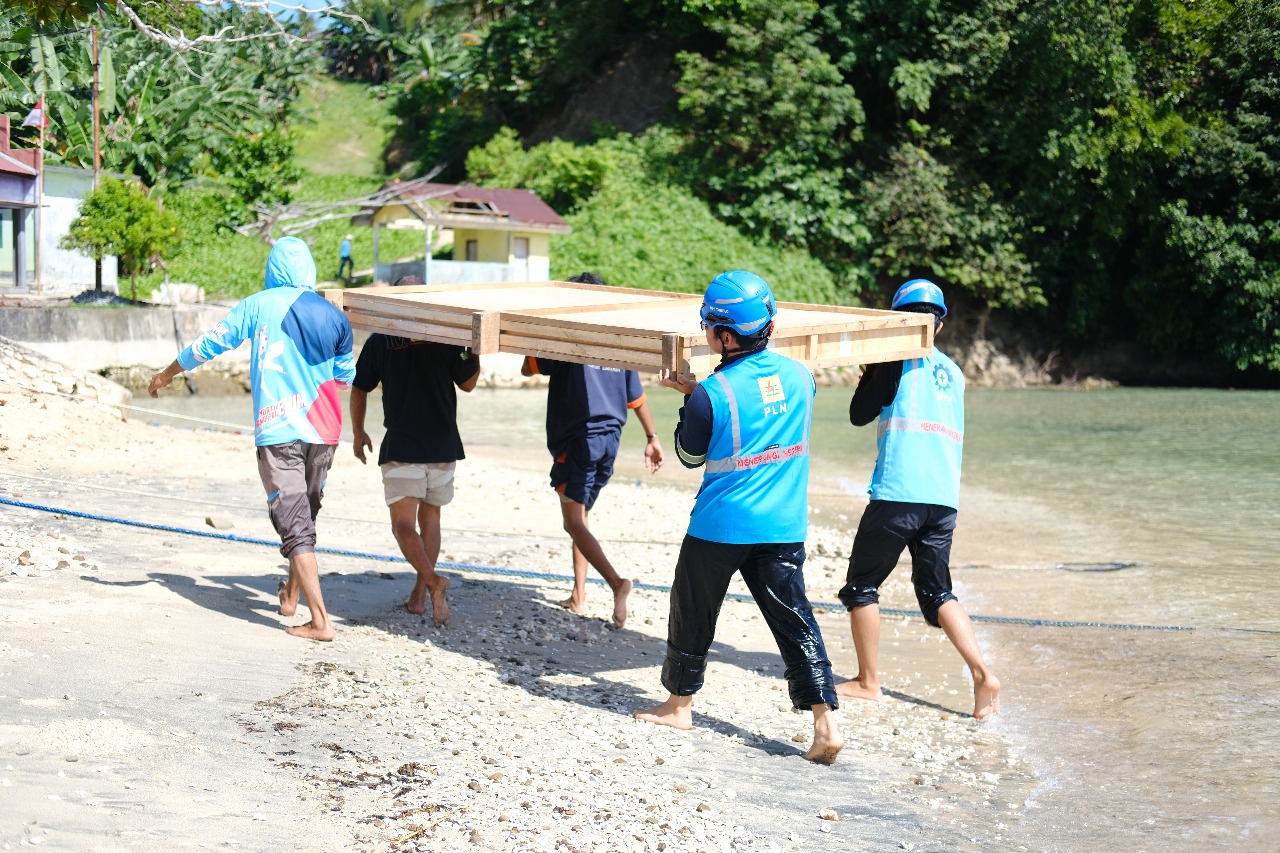 Warga Pulau Dagasuli membantu petugas PLN mengangkut material SuperSun ke sekolah di Maluku Utara.