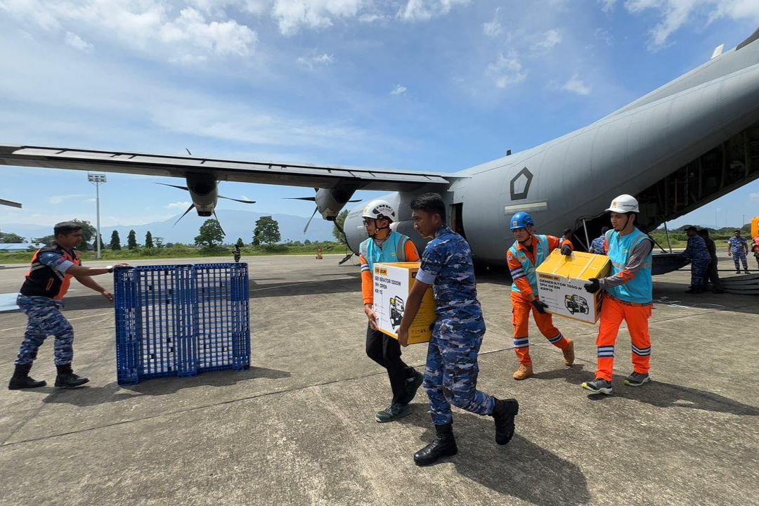 Personel PLN dan TNI AU mengangkut genset serta material tower darurat dari pesawat Hercules di Landasan Udara Sultan Iskandar Muda, Aceh.