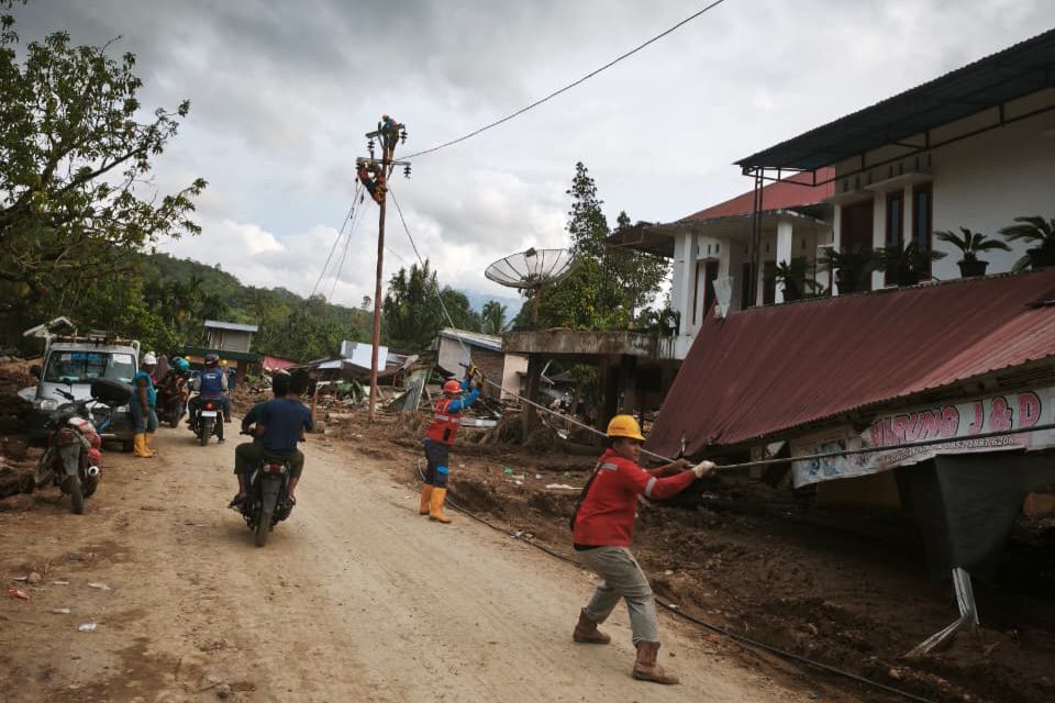 Petugas PLN menarik kabel dan menyambungkannya ke tiang listrik jaringan tegangan rendah baru di Kabupaten Agam sebagai bagian dari pemulihan kelistrikan.
